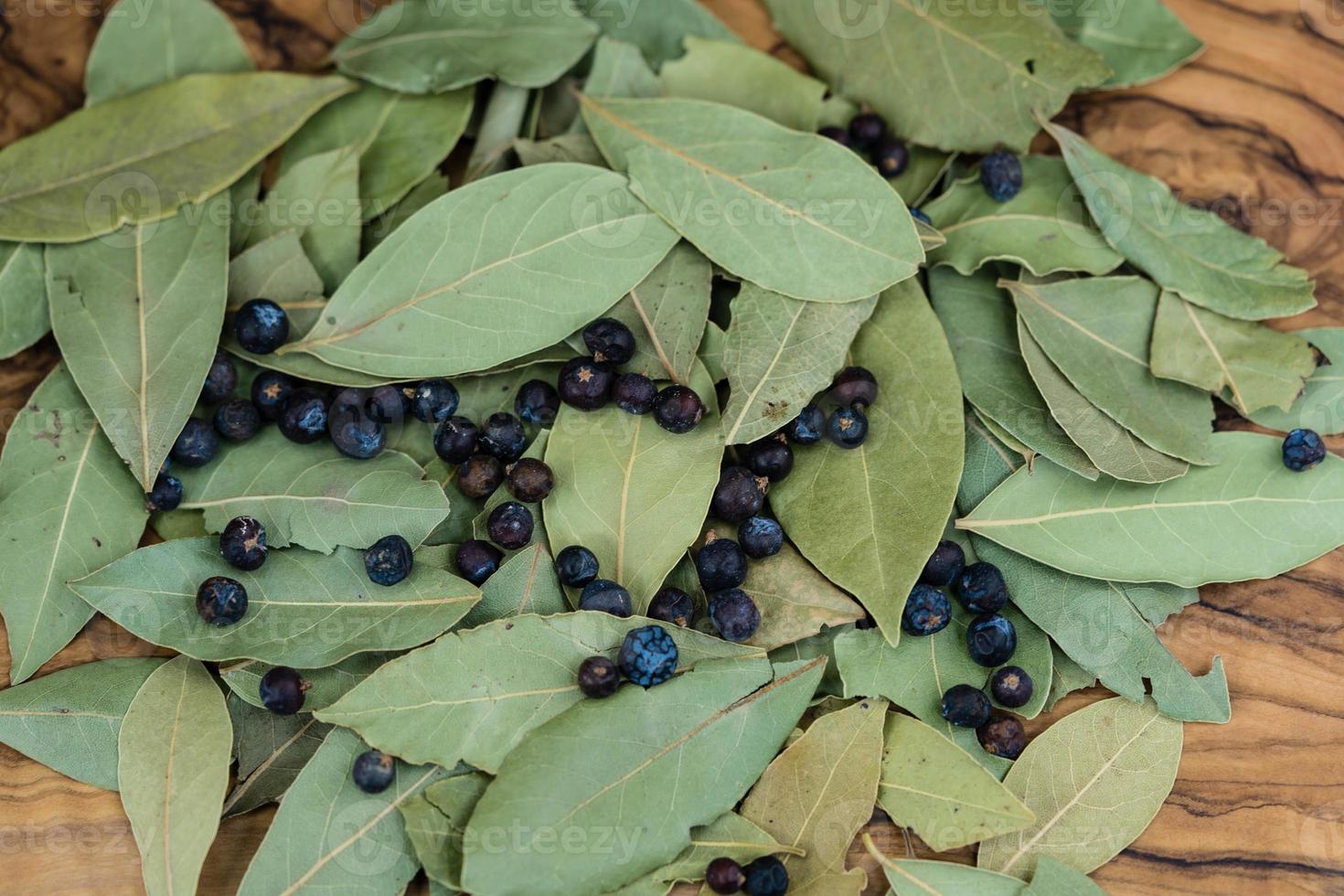 Lorbeerblätter und Wacholderbeeren auf Olivenholz foto