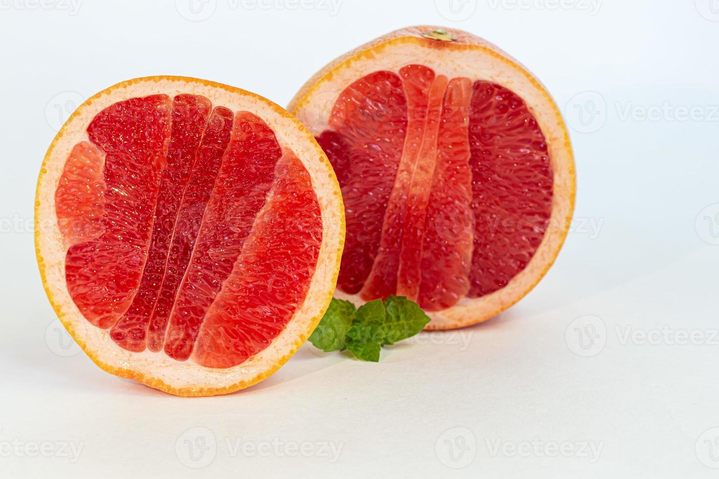 Grapefruit auf einem weißen Teller mit einem Zweig Minze. isolieren. foto