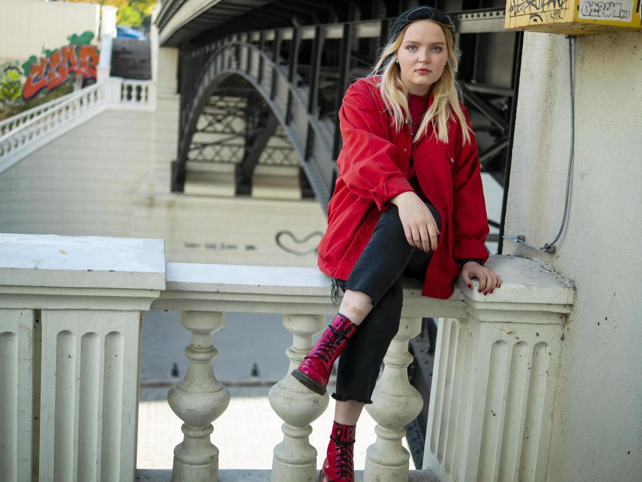 junges blondes Mädchen des Hipsters, das unter einer Brücke sitzt foto