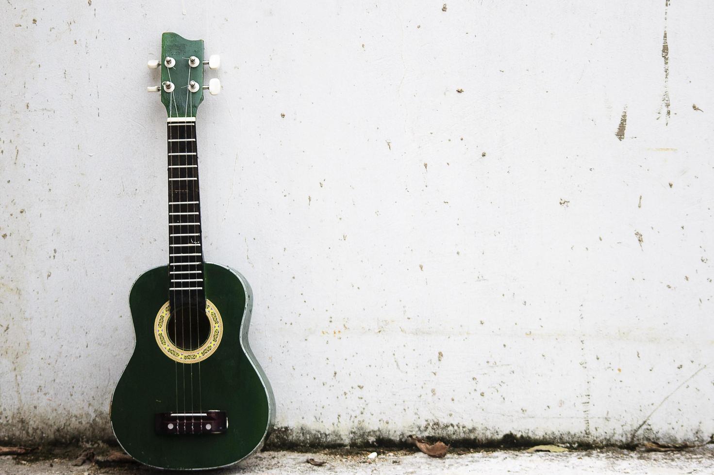 eine grüne Ukulele, die an eine weiße Wand gelehnt ist foto