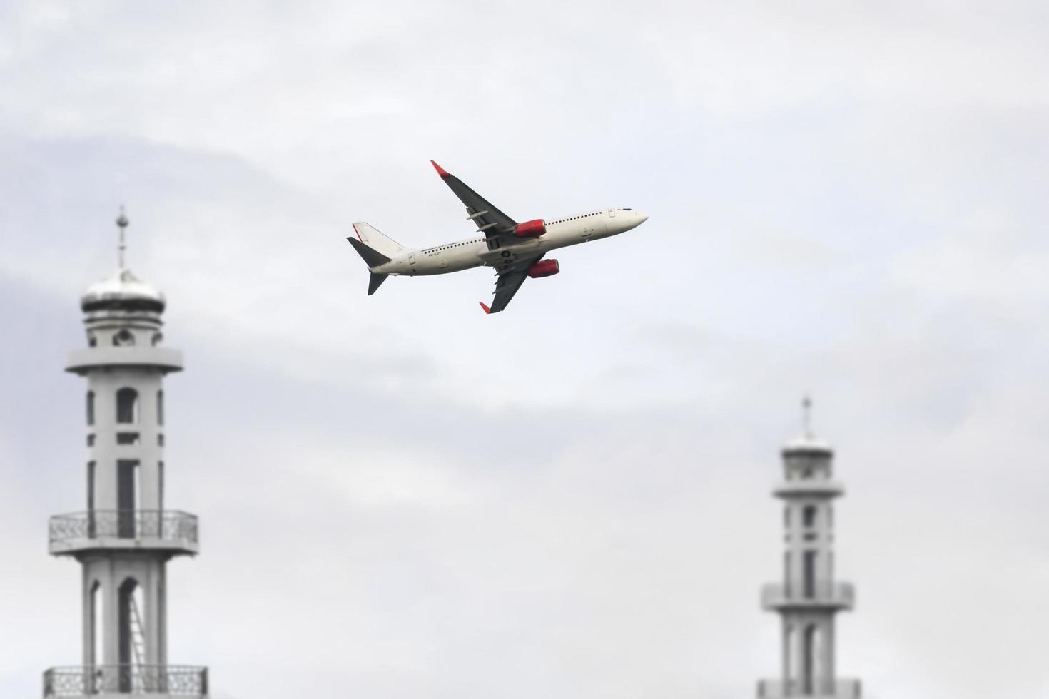 ein Flugzeug fliegt über zwei Minarette einer Moschee foto