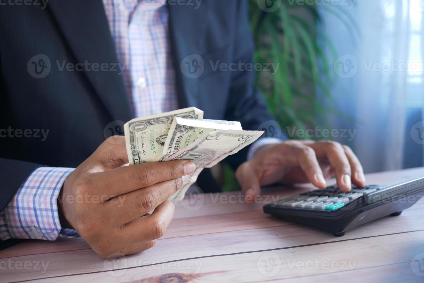 Nahaufnahme der Hand des Mannes mit Taschenrechner und hält uns Dollar? foto