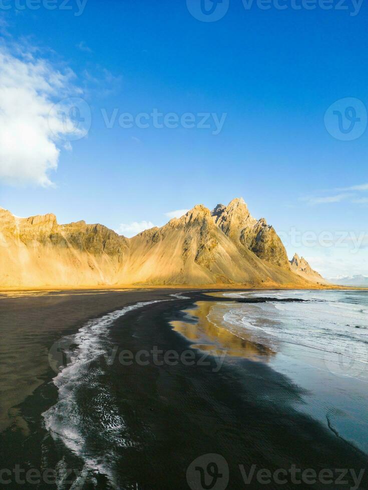 Nord Landschaft entlang Ozean Ufer mit fest Vestrahorn Berg Spitzen im Island. berühmt stokksnes Strand mit isländisch schwarz Sand Strand und nordisch Umfeld, natürlich Horizont. foto