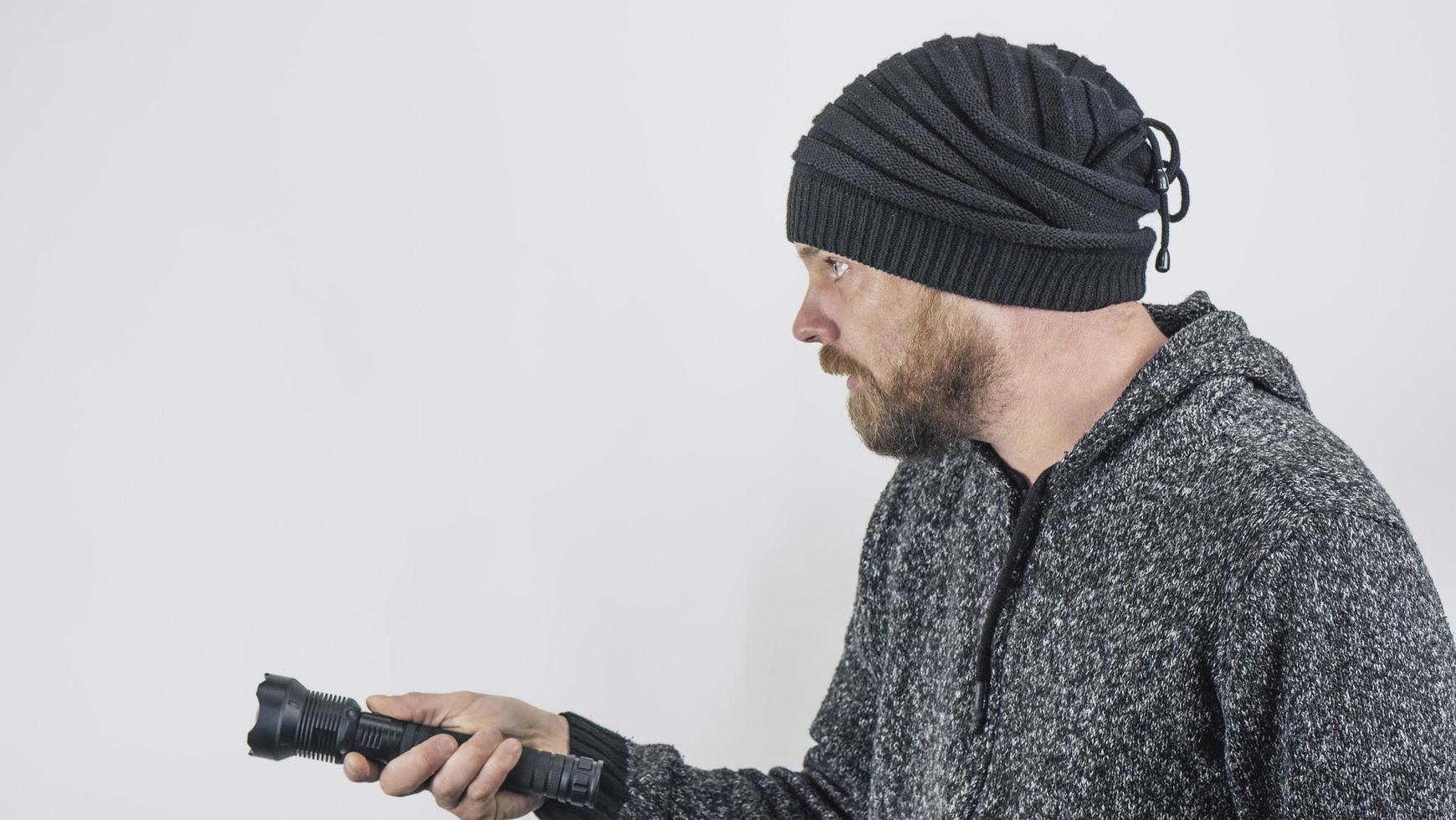 Ein bärtiger Mann hält eine Dioden-Taschenlampe in der Hand foto