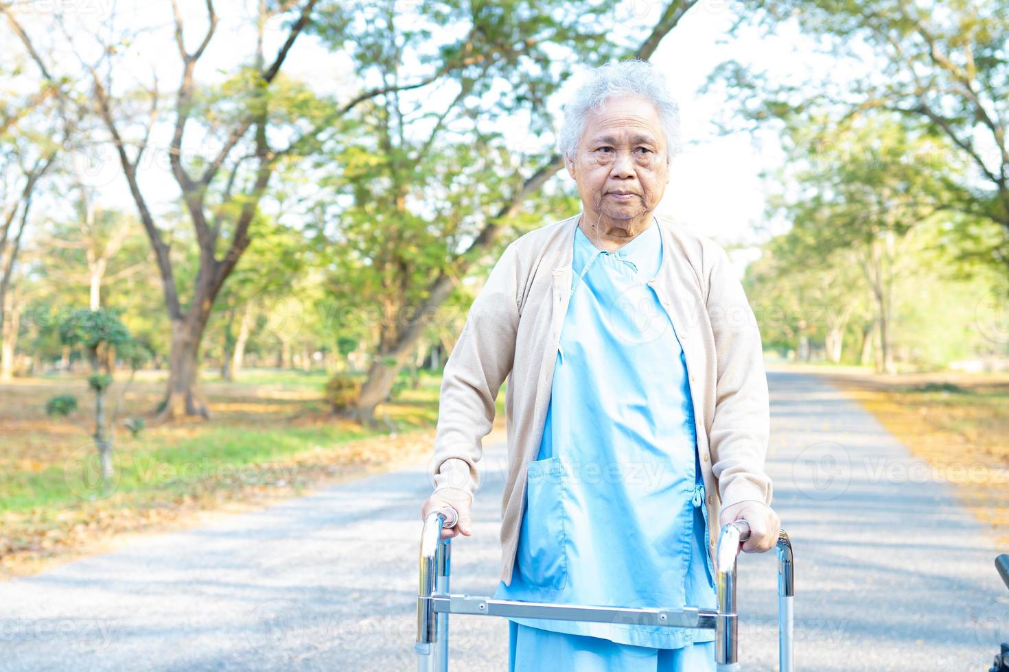 asiatische ältere Frau geduldig Spaziergang mit Gehhilfe im Park foto