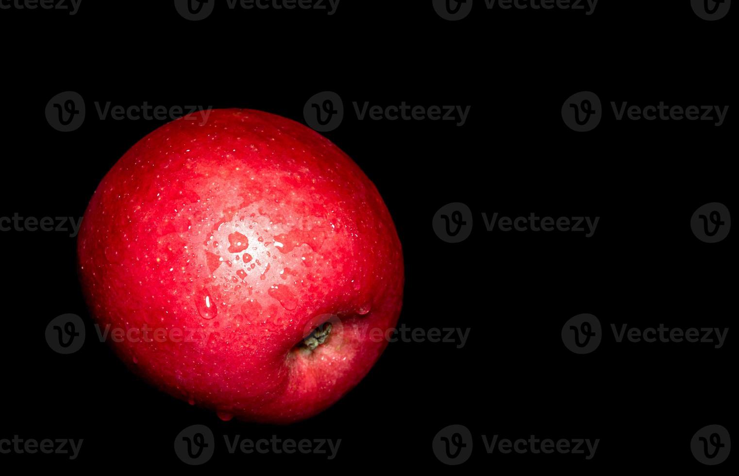 Wassertropfen auf glänzender Oberfläche von rotem Apfel auf schwarzem Hintergrund foto