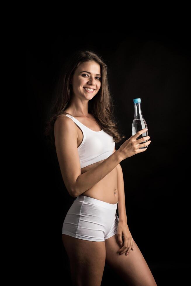 weibliches Fitnessmodel mit einer Wasserflasche foto