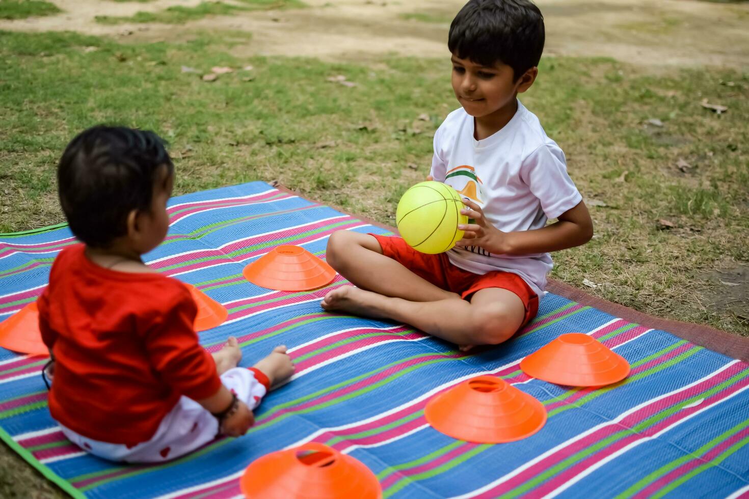 zwei glücklich Jungs im Gesellschaft Park, glücklich asiatisch Brüder Wer sind lächelnd glücklich zusammen. Brüder abspielen draußen im Sommer, Beste Freunde. Kleinkind Baby Junge spielen mit seine glücklich Bruder im das Garten foto