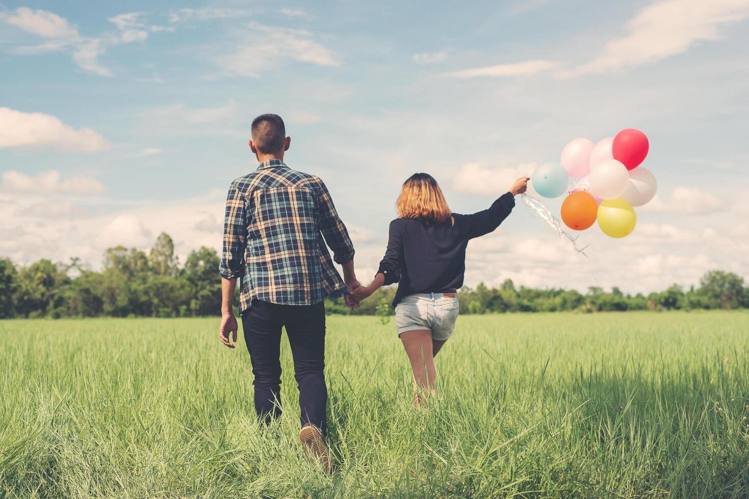 Rückseite des glücklichen jungen asiatischen Paares, das Ballon hält und zusammen geht. foto