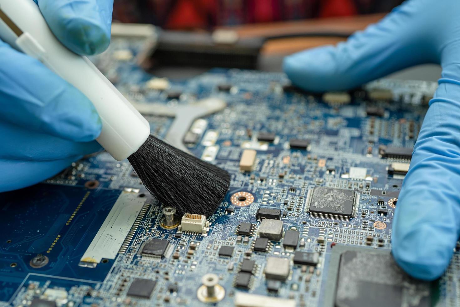 Techniker verwenden Bürste, um Staub im Leiterplattencomputer zu reinigen. foto