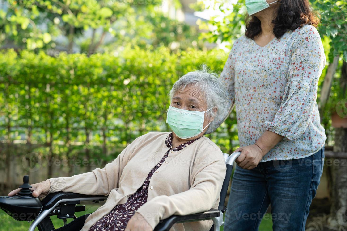 helfen Sie asiatischer Seniorin im Elektrorollstuhl foto
