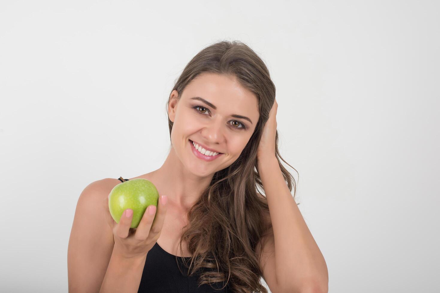 Schönheitsfrau, die grünen Apfel hält, während sie auf weißem Hintergrund lokalisiert wird foto