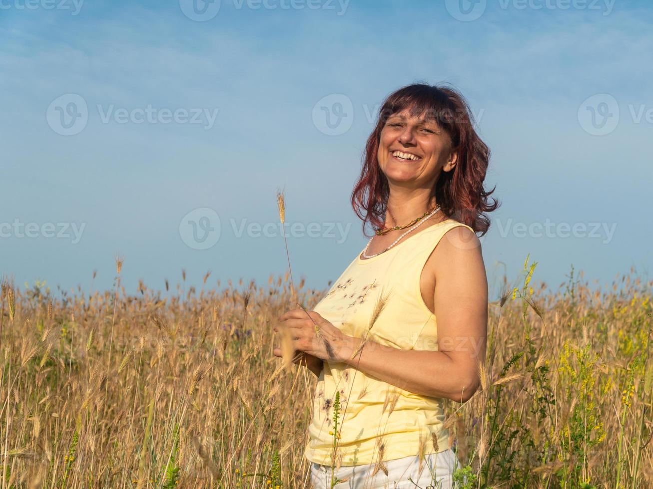 lächelnde Frau im Sommerfeld bei Sonnenuntergang, Positivitätskonzept foto