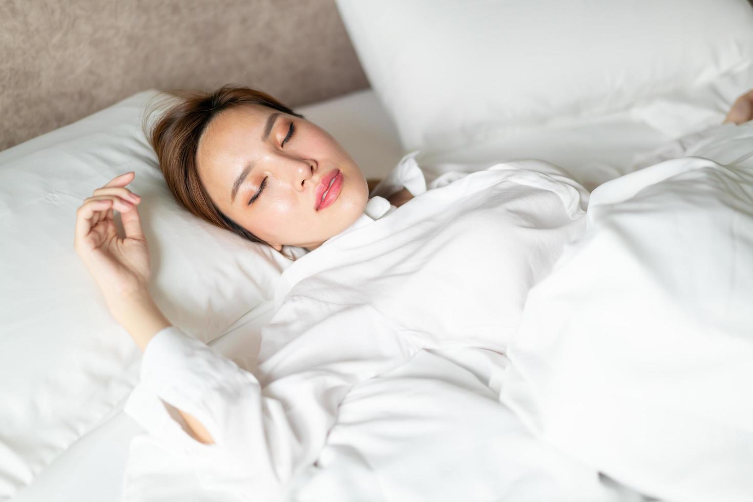 Porträt schöne asiatische Frau, die auf dem Bett mit weißem Kissen schläft foto