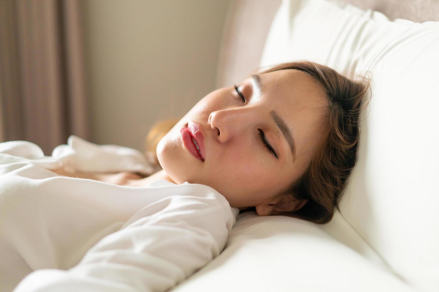 Porträt schöne asiatische Frau, die auf dem Bett mit weißem Kissen schläft foto