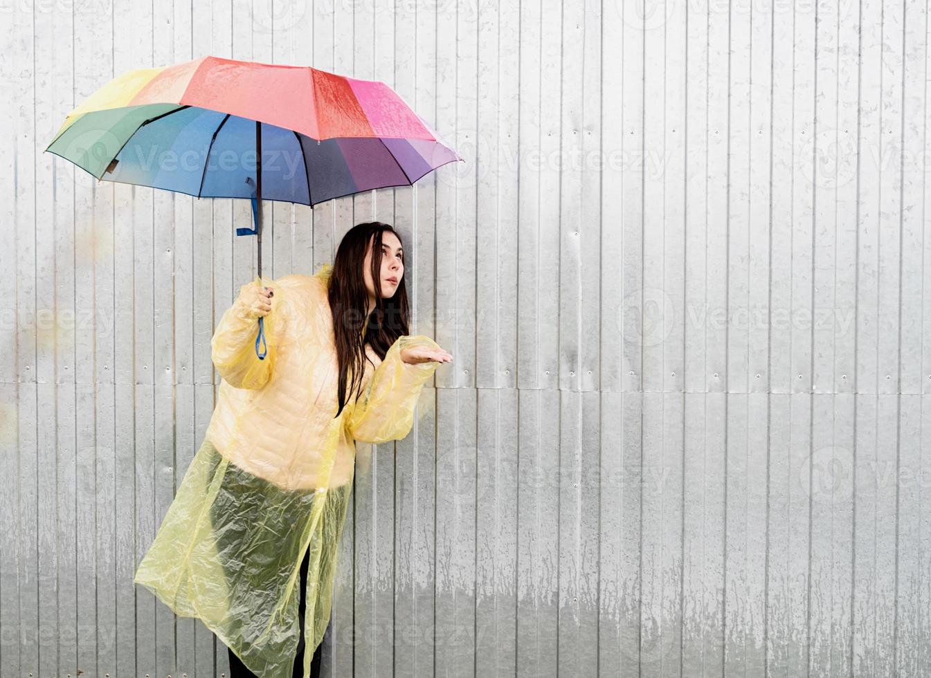 schöne brünette frau mit buntem regenschirm im regen foto
