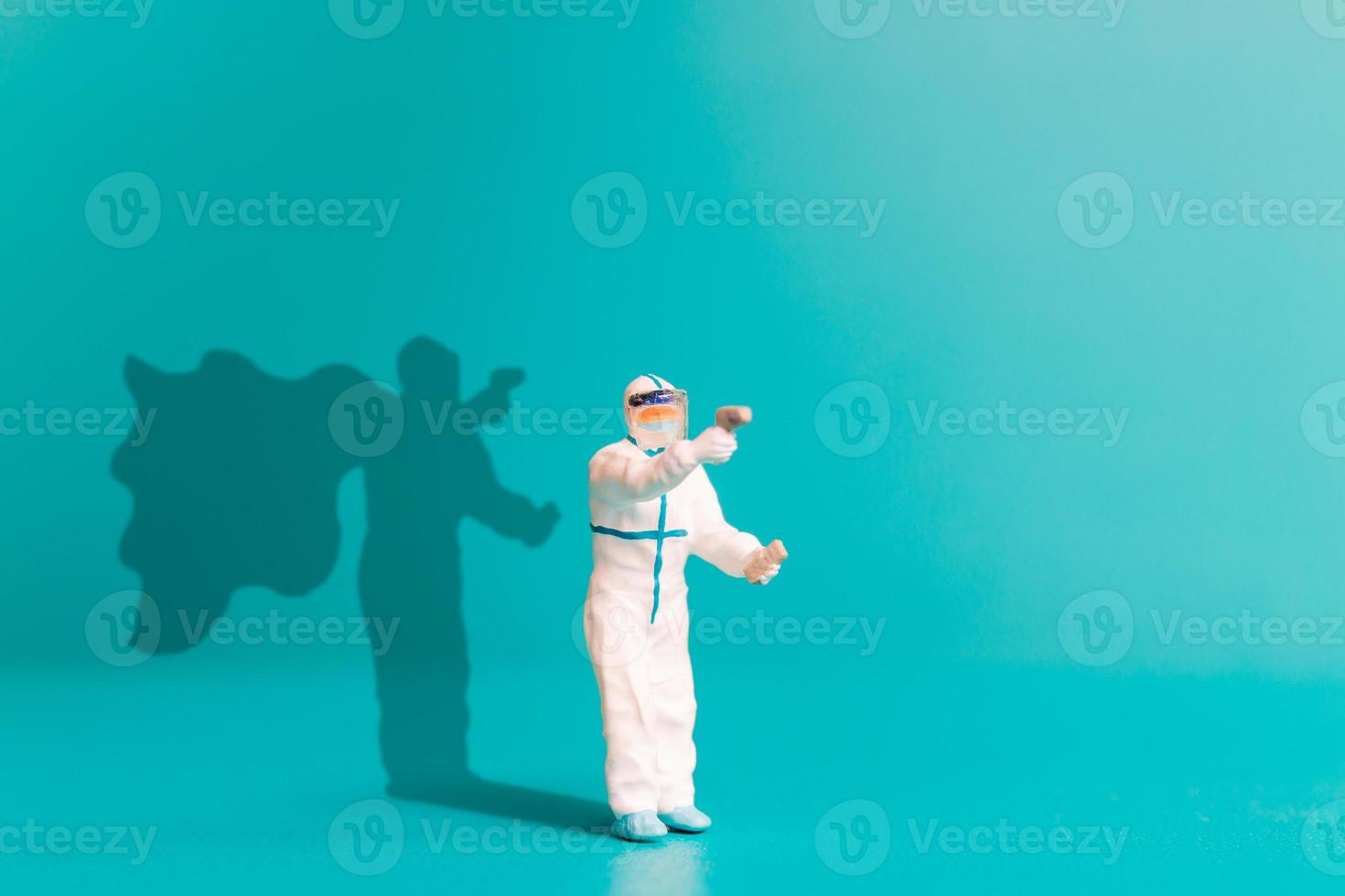 Miniaturmenschenarzt mit Superheldenschatten an der Wand. foto