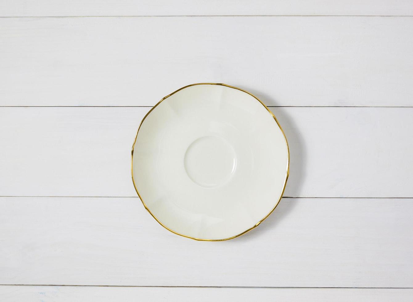 leere runde Keramikplatte auf weißem Holztischhintergrund. Ansicht von oben foto