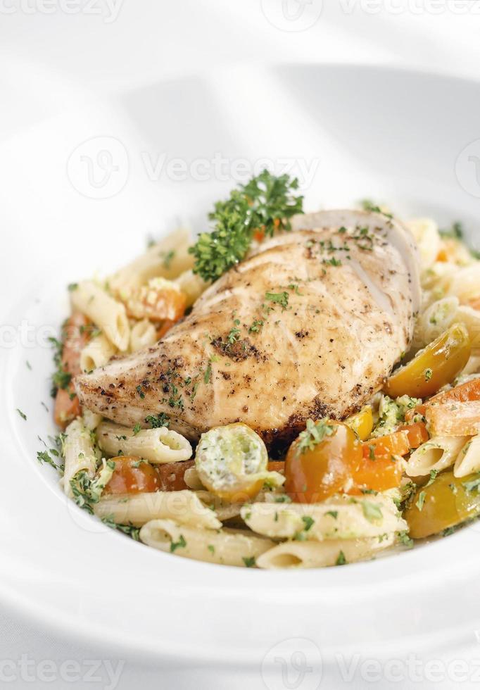 gebratene Hühnerbrust mit Penne und sautiertem Gemüse Nudelgericht auf weißem Hintergrund foto