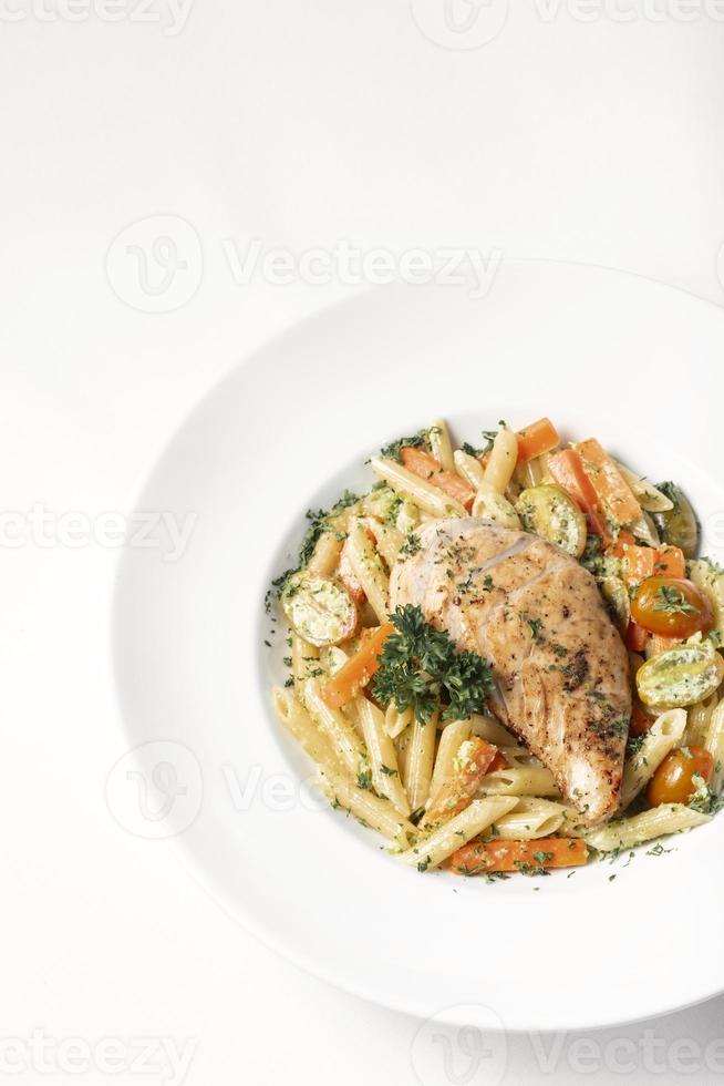 gebratene Hühnerbrust mit Penne und sautiertem Gemüse Nudelgericht auf weißem Hintergrund foto