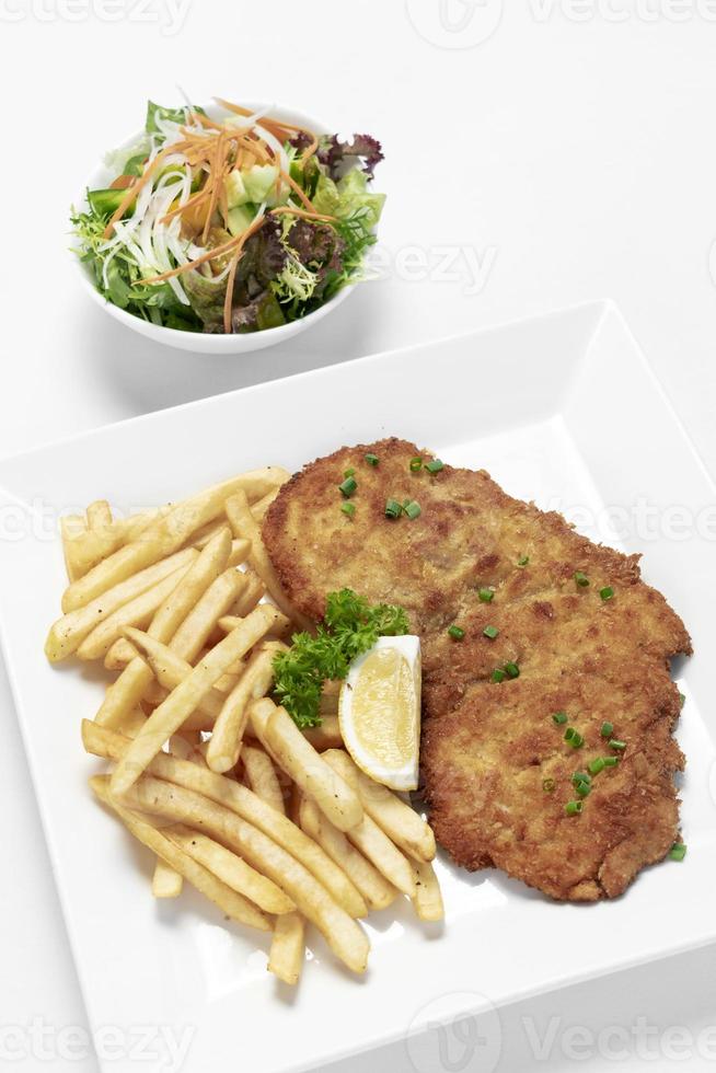 deutsch paniertes Schweineschnitzel mit Pommes frites auf weißem Studiohintergrund foto