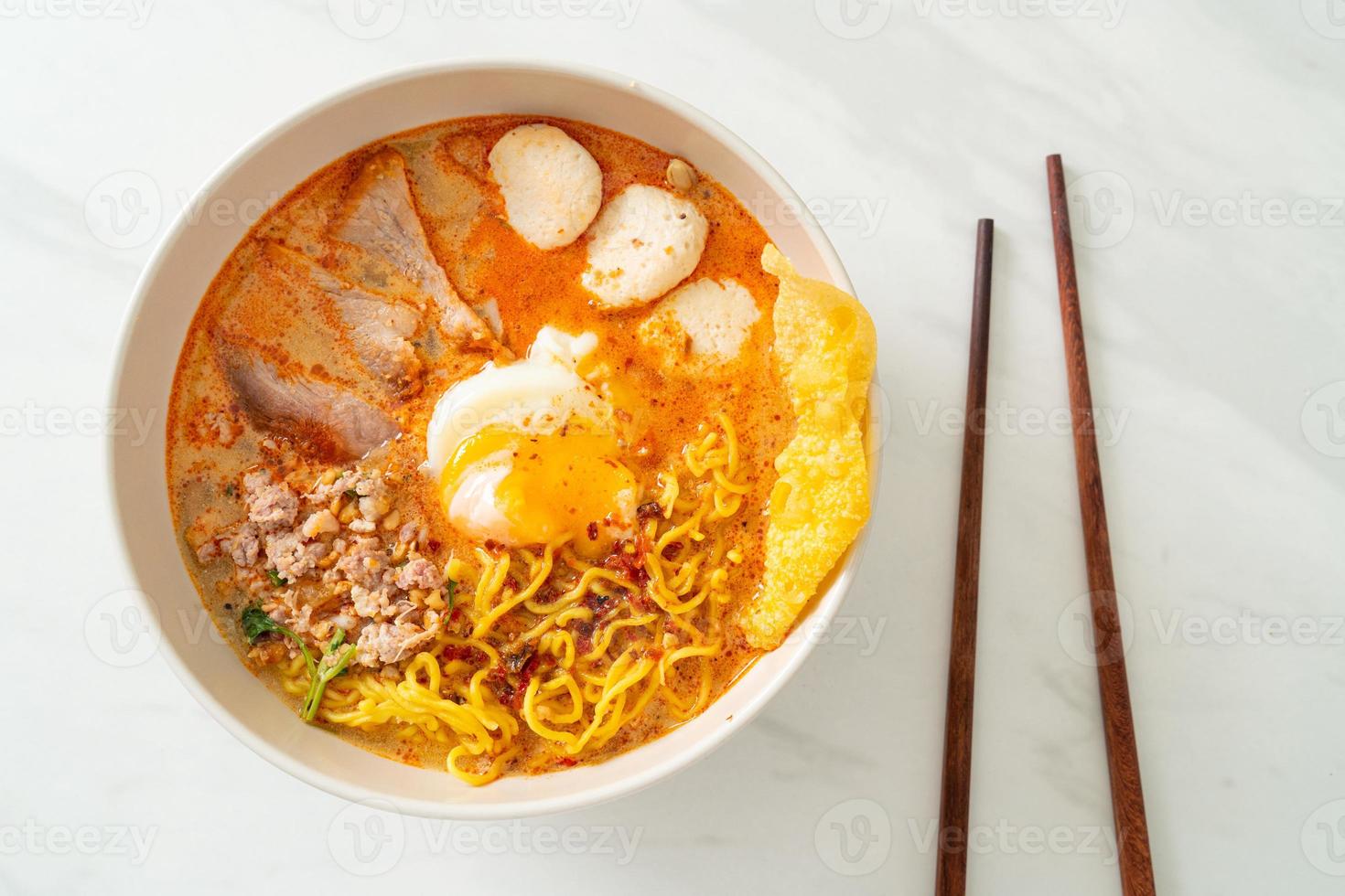 Eiernudeln mit Schweinefleisch und Frikadellen in pikanter Suppe oder Tom Yum Nudeln nach asiatischer Art foto