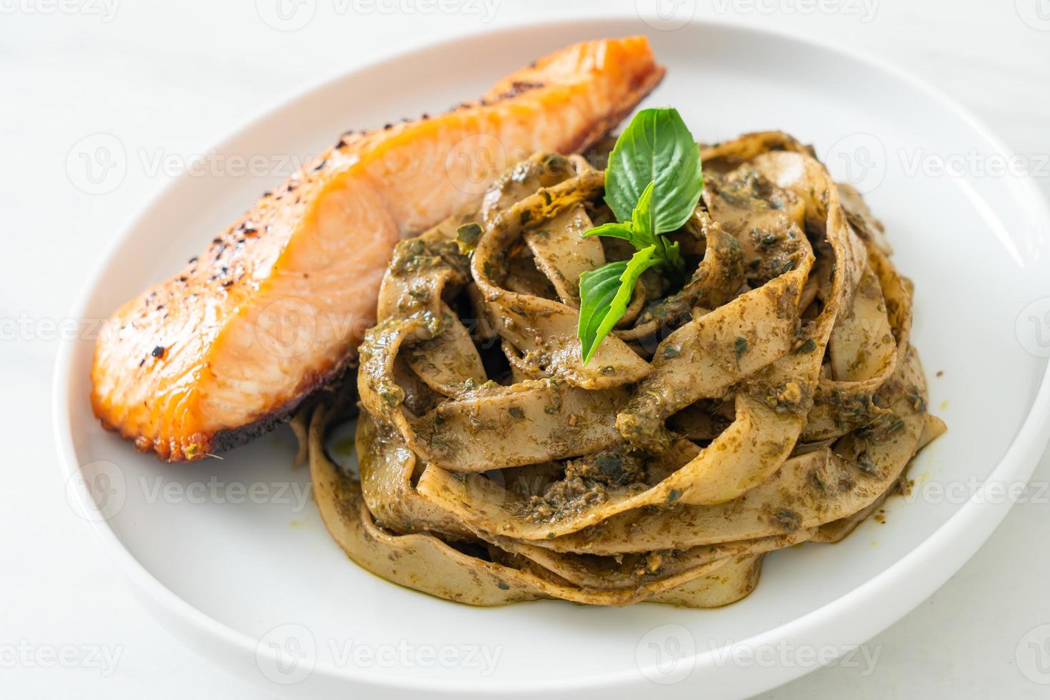 hausgemachte Pesto-Fettuccine-Spaghetti-Nudeln mit gegrilltem Lachsfilet foto