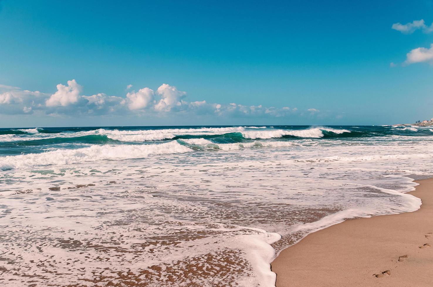 Fußabdrücke im Sand am Strand des Indischen Ozeans, türkisfarbene Wellen foto