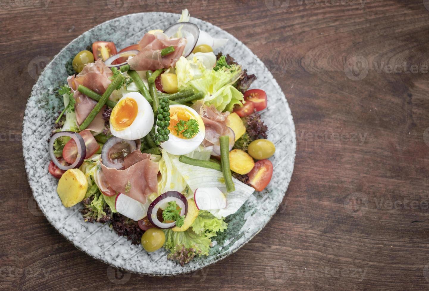 gesunder rustikaler Bio-Salat nach Nicoise-Art mit Ei und Schinken im Freien foto