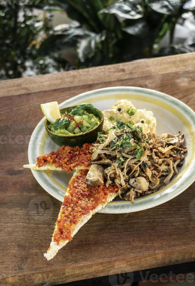 moderner mexikanischer Brunch aus gebratenen Champignons mit Guacamole und würzigem Paprika-Toast und Rührei foto