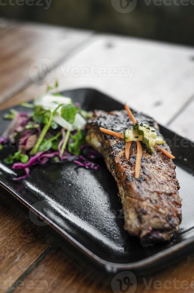 marinierte gegrillte Schweinerippchen vom Grill mit Salat und eingelegtem Gemüse foto