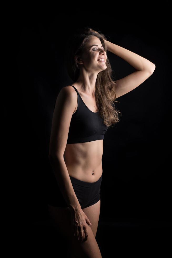 schöne Frau mit gesundem Körper auf schwarzem Hintergrund foto
