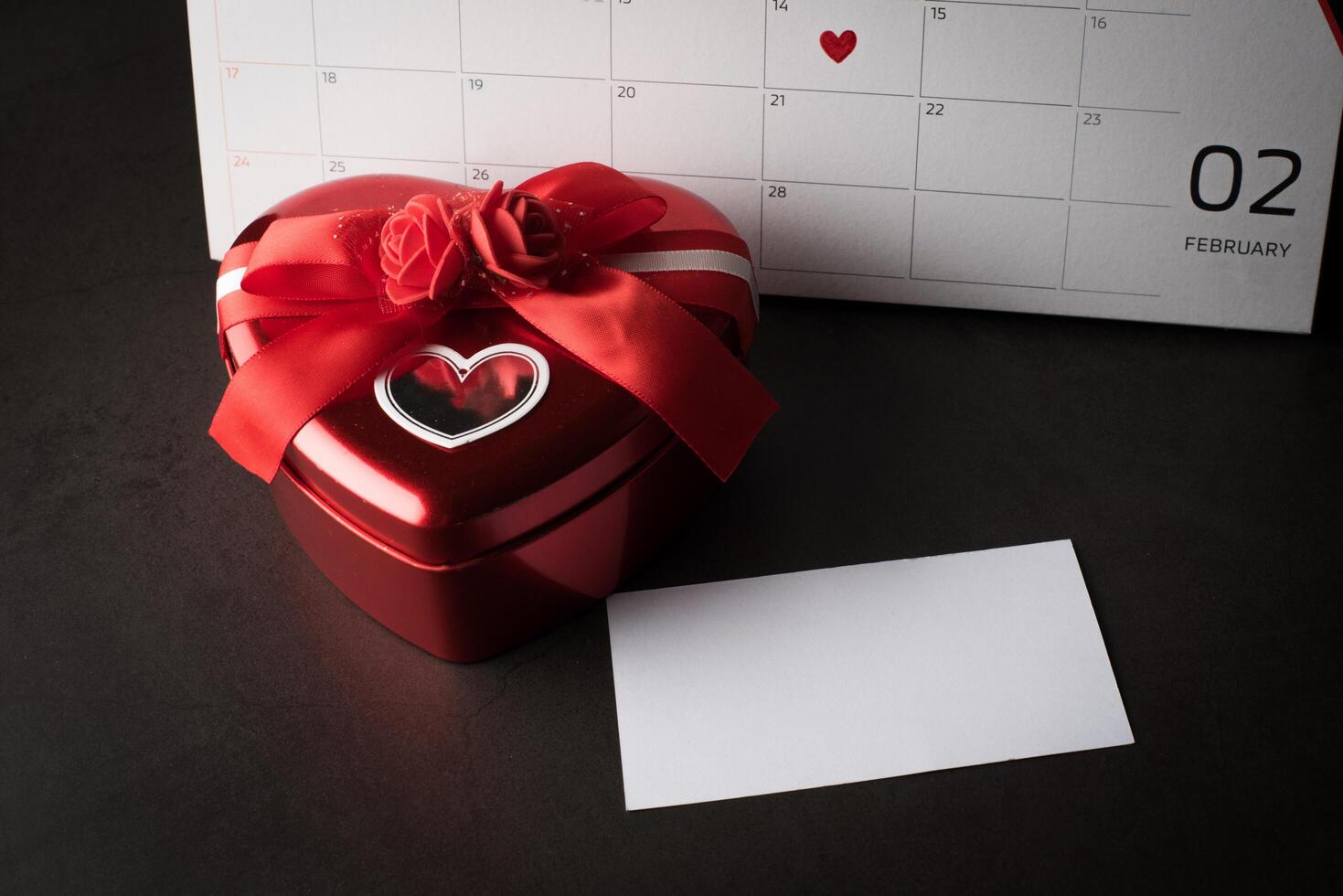 rotes Herz im 14. Februar auf dem Kalender mit Herzform. Geschenkbox. foto