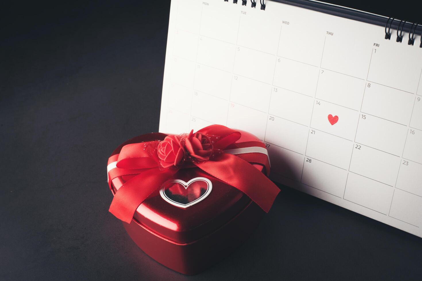 rotes Herz im 14. Februar auf dem Kalender mit Herzform. Geschenkbox. foto