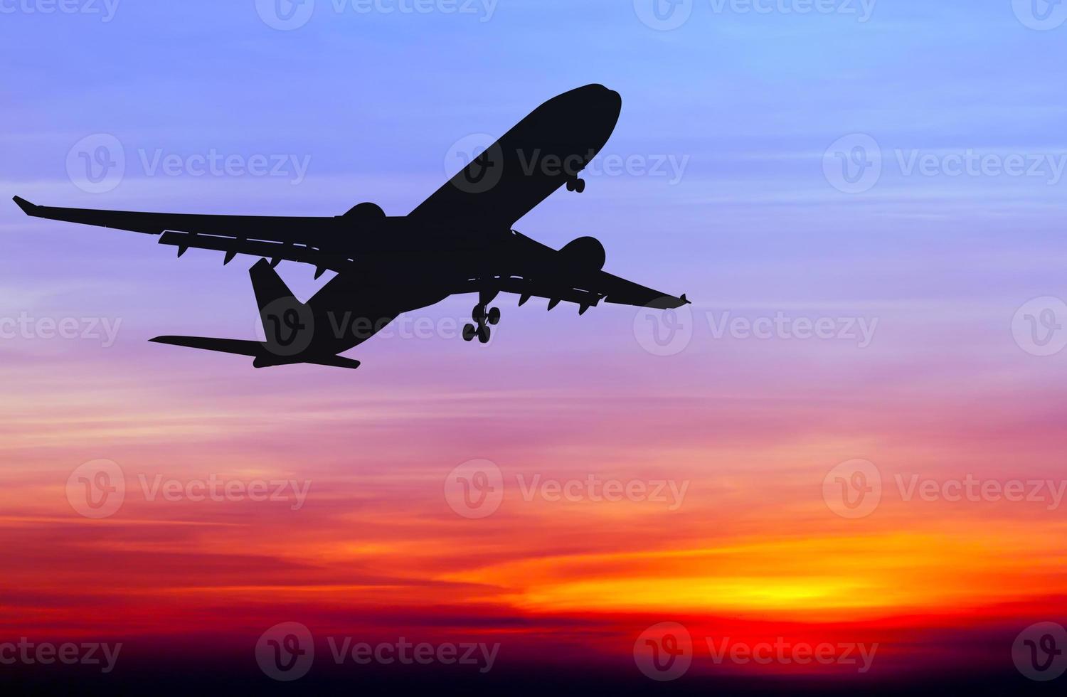 Silhouette eines kommerziellen Flugzeugs, das bei Sonnenuntergang fliegt foto