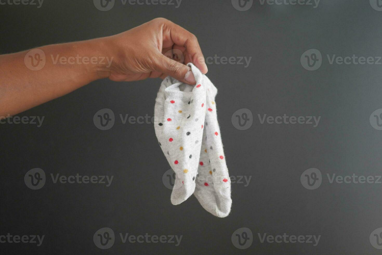 halten ein Paar von schmutzig Socken gegen schwarz Hintergrund foto