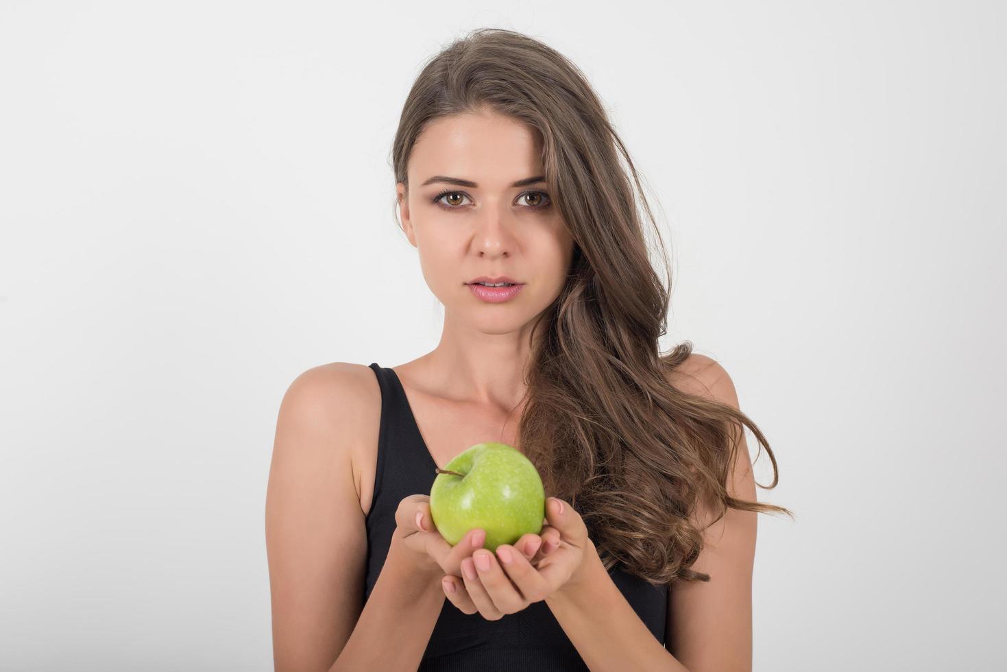 Schönheitsfrau, die grünen Apfel hält, während sie auf Weiß lokalisiert wird. foto