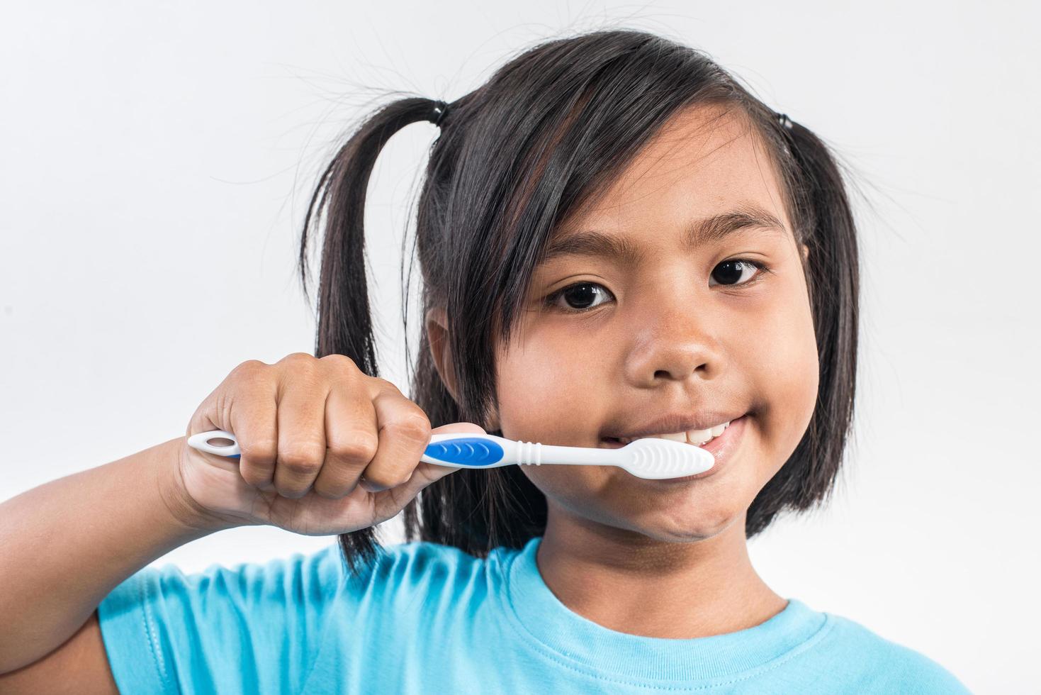 kleines Mädchen beim Zähneputzen in Studioaufnahme foto