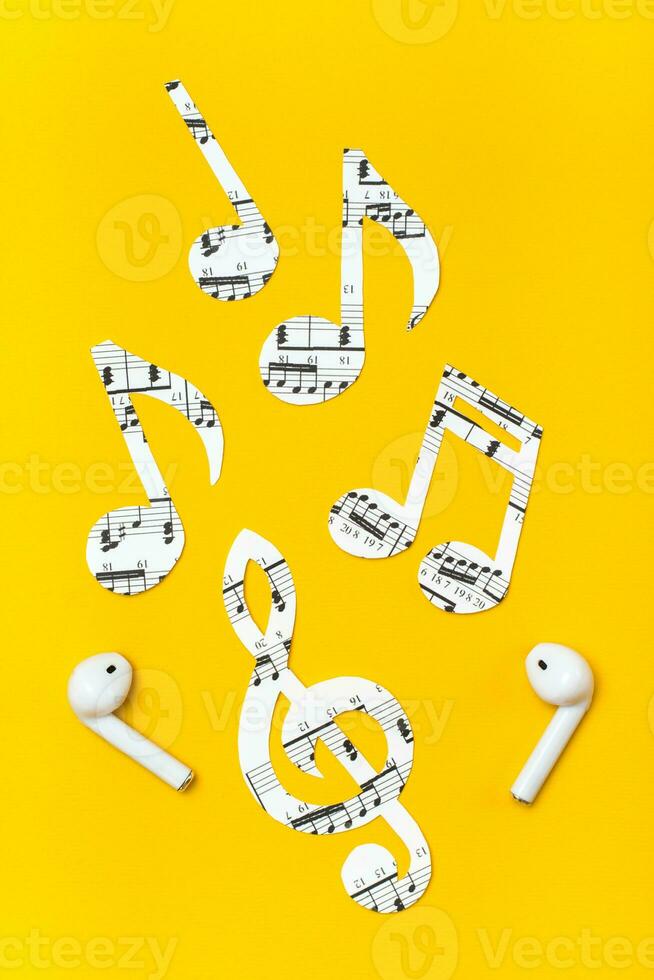 kabellos Kopfhörer und Musik- Anmerkungen Schnitt von Papier auf ein Gelb Hintergrund. Musik- Nachahmung Konzept. Vertikale Aussicht foto