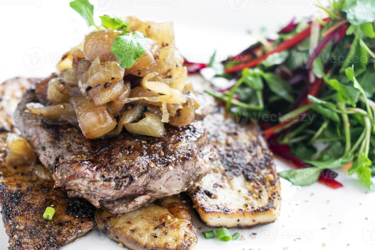 Rindersteak mit gegrillten Champignons und karamellisierten Zwiebeln Gourmetessen auf weißem Teller foto