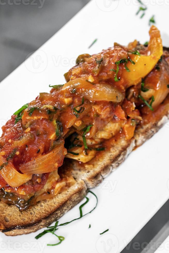 portugiesische Caldeirada de Peixe scharfe Tomaten-Zwiebel-Paprika-Fisch-Eintopf auf rustikalem Tiborna-Toast nach Tapas-Art foto