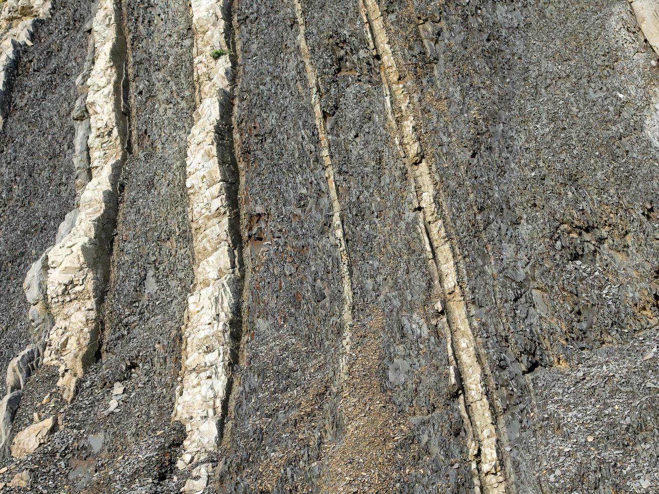 Bergfelsen aus grauen, weißen, braunen Farbsteinen in diagonaler Schicht foto