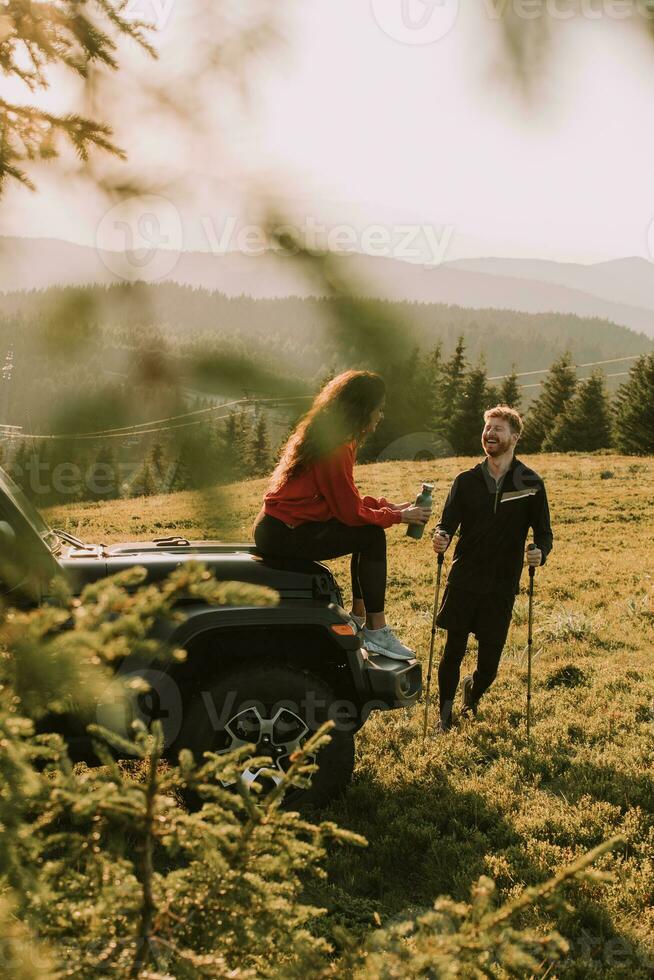 junges paar, das sich durch eine geländefahrzeughaube auf dem land entspannt foto