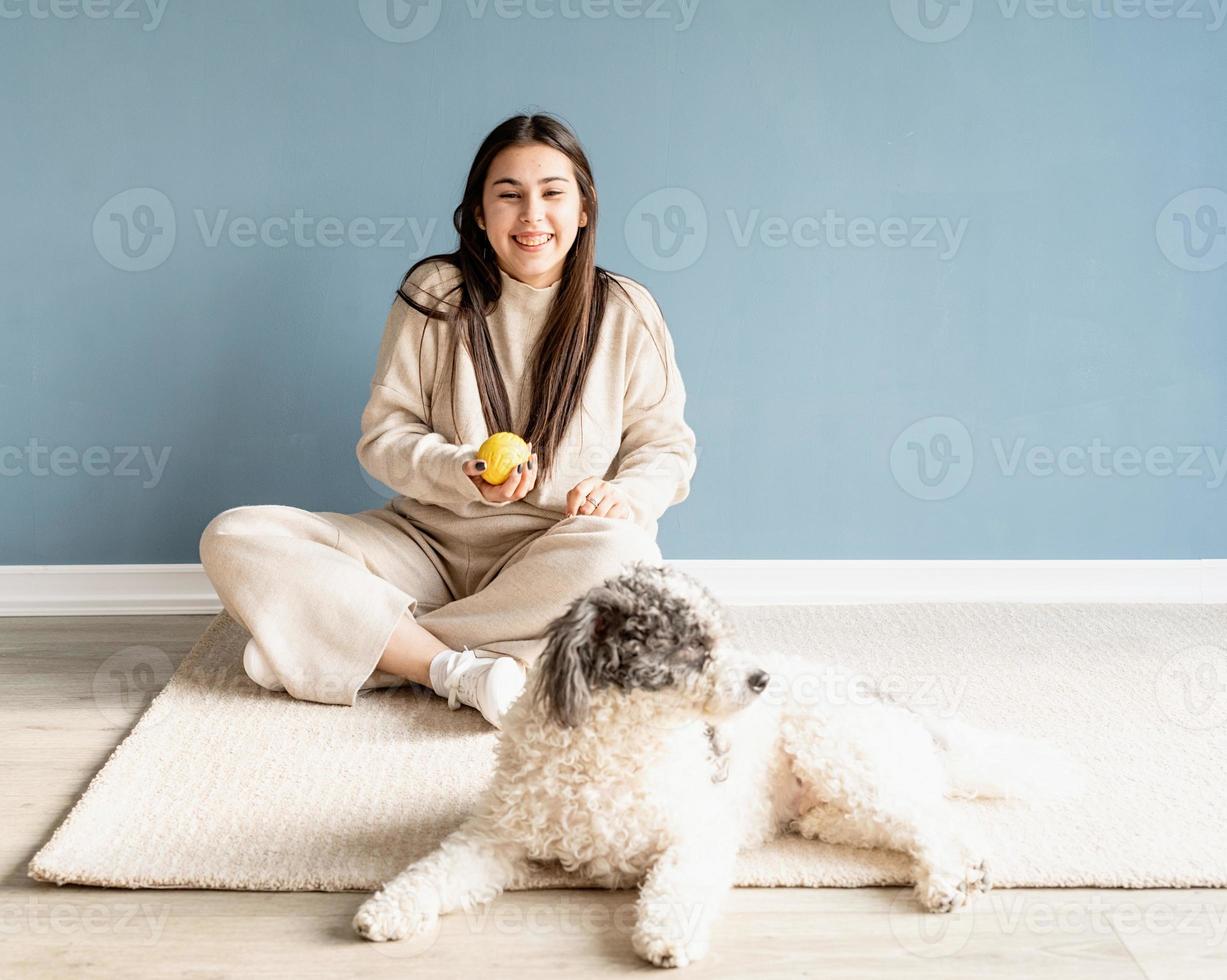 schöne Frau mit Mischlingshund, der zu Hause Ball spielt foto