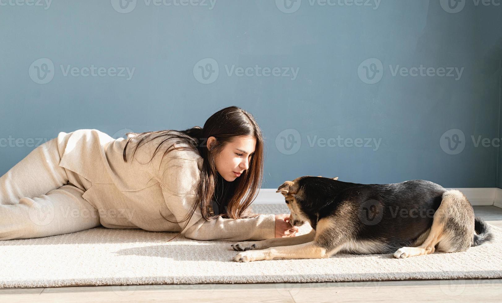 schöne Frau mit verspieltem Hund, die sich zu Hause umarmt foto