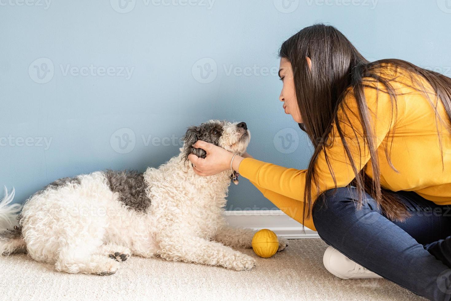 schöne frau mit verspieltem jungem hund, der spaß zu hause hat foto