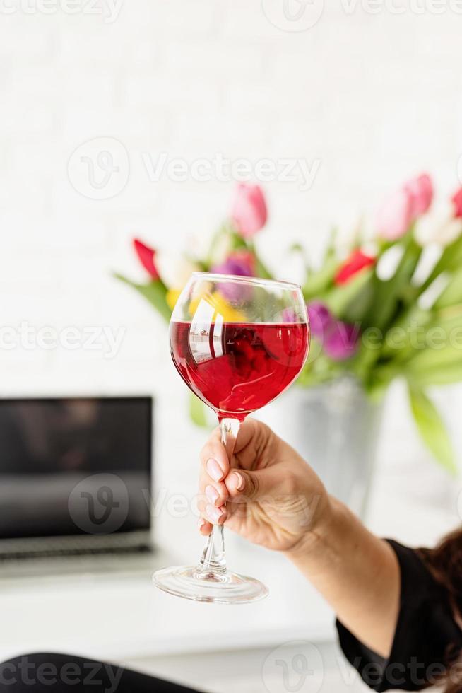 Frauenhand hält ein Glas Rotwein und feiert Frühlingsferien foto