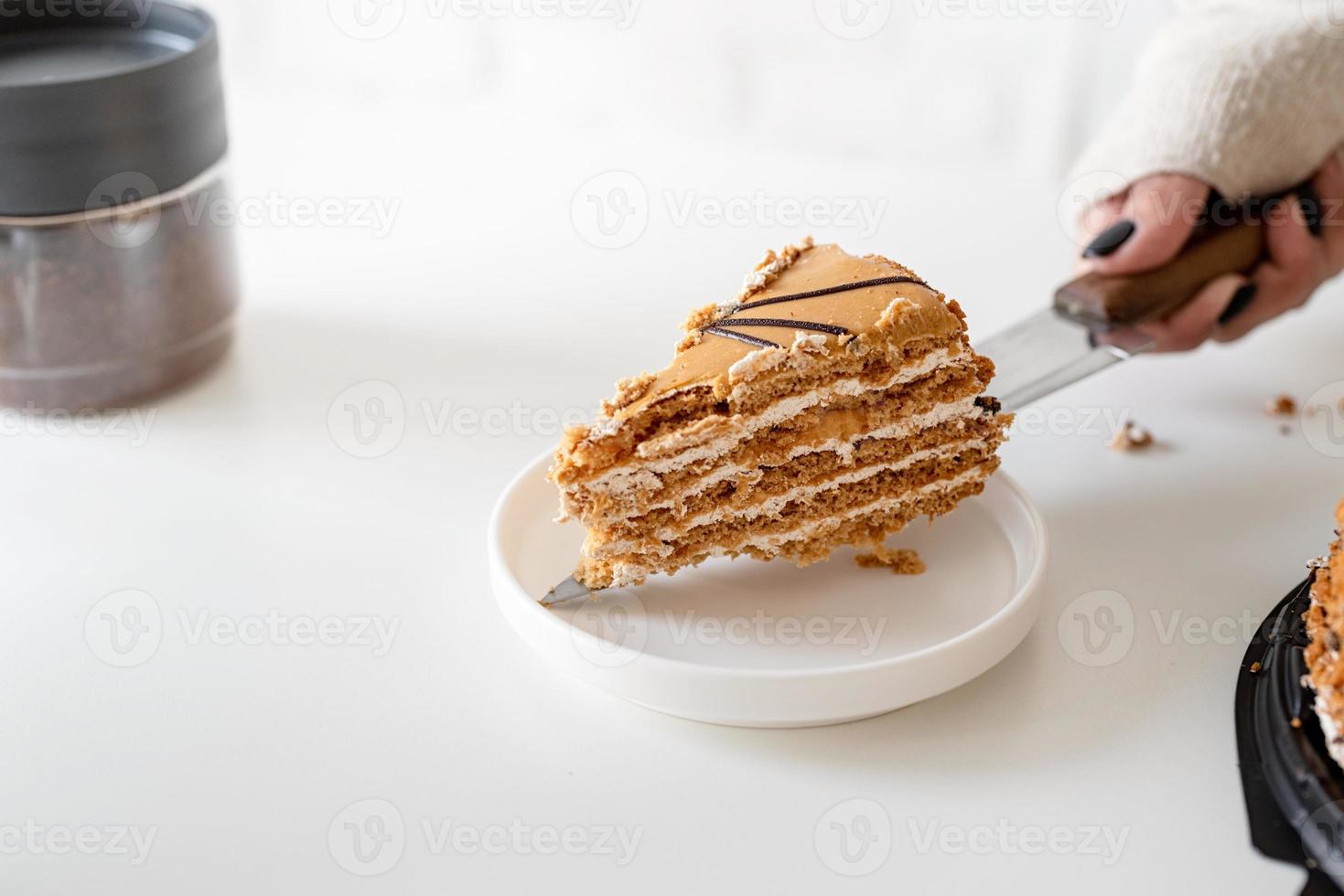 Nahaufnahme von Frauenhänden, die einen Kuchen schneiden foto