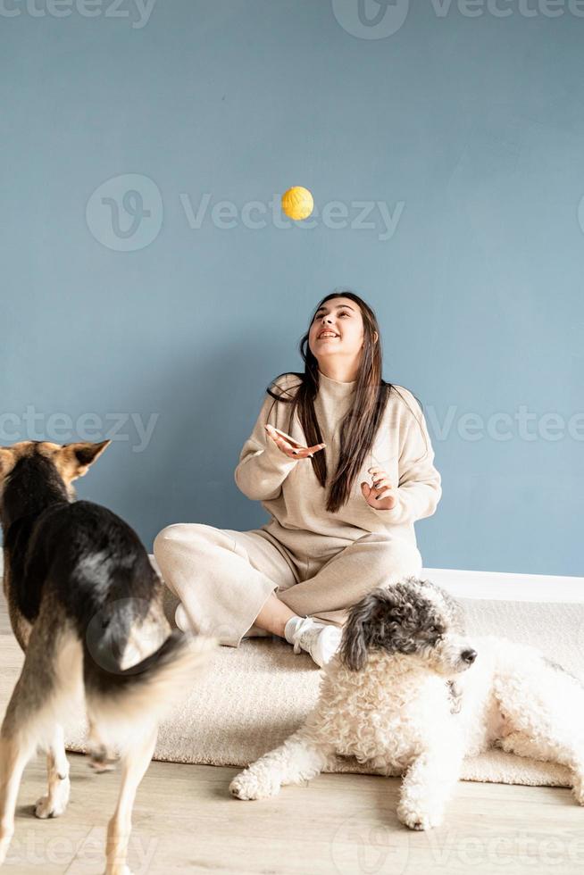 schöne Frau mit Mischlingshund, der zu Hause Ball spielt foto