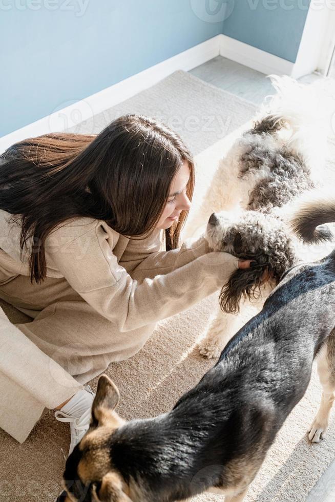 schöne Frau mit verspieltem Hund, die sich zu Hause umarmt foto